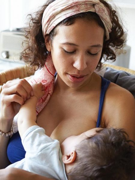 Infancy, motherhood, nutrition, lactation and breastfeeding concept. Indoor portrait of tender attractive young mom nursing her baby boy, giving him all love and affection, sitting in bedroom